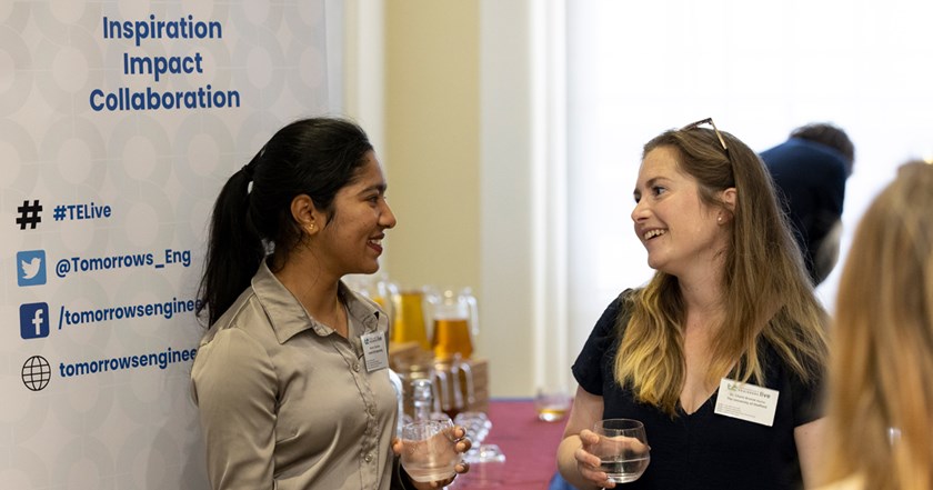 Two conference attendees drinking water and smiling while having a conversation